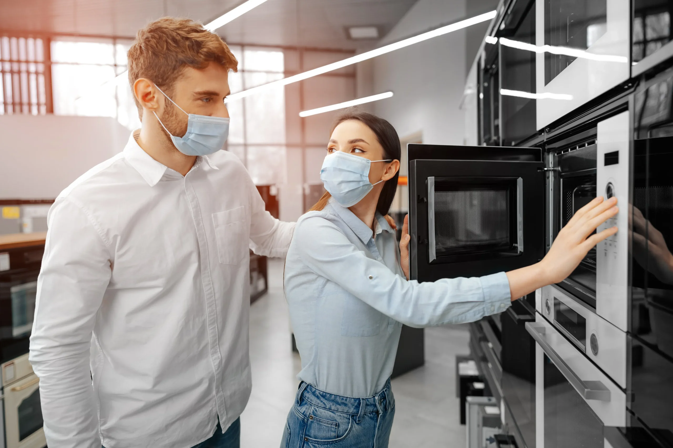 young couple wearing medical masks hypermarket with home appliances scaled